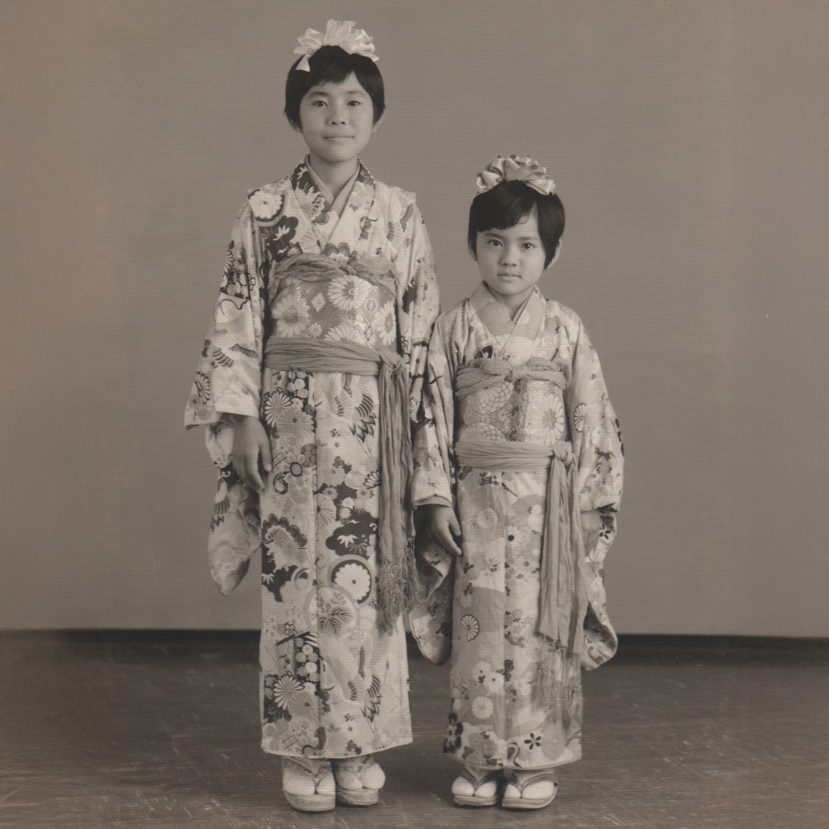 Sueko Oshimoto and her sister in traditional Japanese kimono standing against a plain background in 1968.